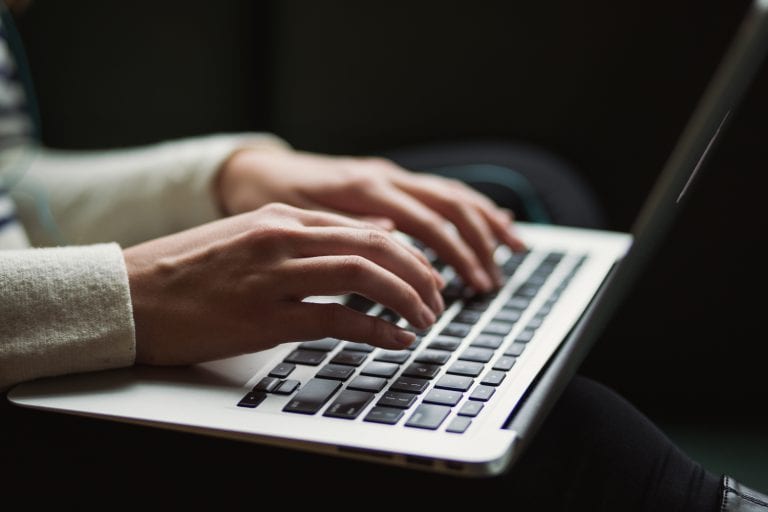 Hands typing on laptop keyboard